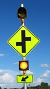 Figure 29. Photo. C-V12, lap A study assembly. An Offset Side Roads sign assembly with one 12-inch circular beacon above the W2-7L sign and one 12-inch circular beacon between the W2‑7L sign and the W16-7P arrow plaque. Figure 29. Photo. C-V12, lap A study assembly. An Offset Side Roads sign assembly with one 12-inch circular beacon above the W2-7L sign and one 12-inch circular beacon between the W2‑7L sign and the W16-7P arrow plaque.