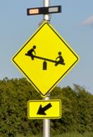 Figure 32. Photo. R-A, lap B study assembly. A Playground sign assembly with a set of rectangular beacons above the W15-1 sign and the W16-7P arrow plaque, shown at night. Figure 32. Photo. R-A, lap B study assembly. A Playground sign assembly with a set of rectangular beacons above the W15-1 sign and the W16-7P arrow plaque, shown at night.