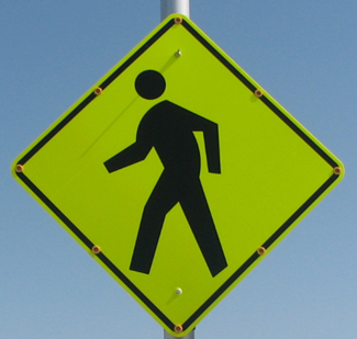 Figure 40. Photo. Discomfort glare assembly with embedded LEDs. A Pedestrian Crossing sign with yellow light-emitting diodes embedded in eight places (each corner and the midpoint of each side) on the black border of the sign.