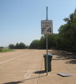 Figure 51. Photo. Trash can on course. The trash can used in the study is shown in position on the closed course 3 ft behind a sign post. Figure 51. Photo. Trash can on course. The trash can used in the study is shown in position on the closed course 3 ft behind a sign post.