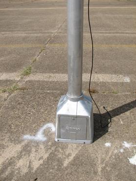 Figure 54. Photo. Base for signs with beacons/LEDs. A close-up of the base used to support the signs that have beacons or light-emitting diodes.The base is about 18 inches by 18 inches where it is touching the pavement. Figure 54. Photo. Base for signs with beacons/LEDs. A close-up of the base used to support the signs that have beacons or light-emitting diodes.The base is about 18 inches by 18 inches where it is touching the pavement.