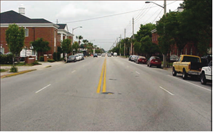 Figure 104. Photo. Four-lane configuration before road diet. A four-lane undivided roadway with on-street parking on both sides of the street, from a driver’s perspective on the centerline of the street.
