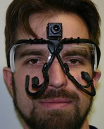 Figure 61. Photo. MPI system performance experiment—eye-tracker goggles. The figure shows a photo of a man wearing the eye-tracker goggles. Two cameras are aimed at the man’s eyes, and a camera mounted on the goggles at his forehead is aiming straight ahead.