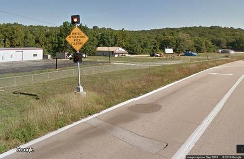 Figure 1. Photo. ICWS visual display from Google Street ViewTM. This photograph shows a post-mounted warning sign with flashing beacons above and below the sign face displaying the message stating "TRAFFIC APPROACHING WHEN FLASHING."