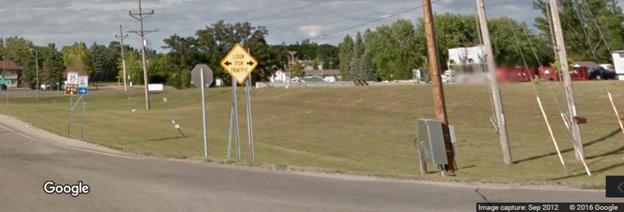 Figure 9. Photo. Minor route sign with LED arrow-shaped flashers from Google Street ViewTM. This photograph shows a post-mounted warning sign with the message "LOOK FOR TRAFFIC" with light emitting diode left- and right-facing arrows.