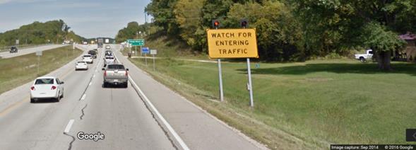 Figure 11. Photo. Major route static sign with flashing beacons from Google Street ViewTM. This photograph shows a post-mounted warning sign on a divided highway stating "WATCH FOR ENTERING TRAFFIC" with two flashing beacons.