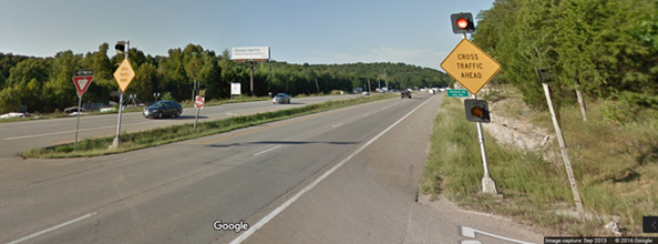 Figure 13. Photo. Dual major route static sign with flashing beacons from Google Street ViewTM. This photograph shows a post-mounted warning sign on a divided highway stating "CROSS TRAFFIC AHEAD" with two flashing beacons.