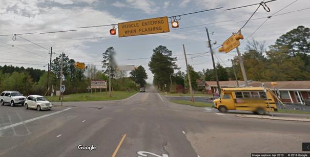 Figure 14. Photo. Major and minor route overhead static signs with flashing beacons from Google Street ViewTM. This photograph shows overhead warning signs stating "VEHICLE ENTERING WHEN FLASHING" on the major road and "WATCH FOR APPROACHING VEHICLE" on the minor road, both with two flashing beacons.