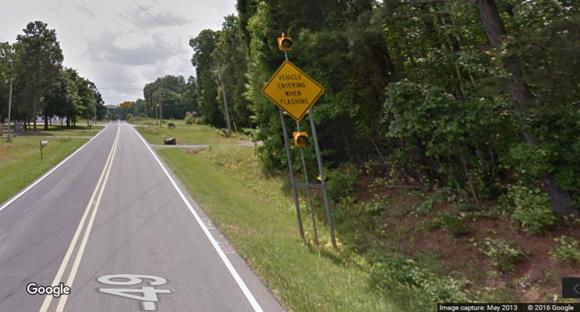 Figure 16. Photo. Major route static sign with flashing beacons from Google Street ViewTM. This photograph shows a post-mounted sign stating "VEHICLE ENTERING WHEN FLASHING" with two flashing beacons.