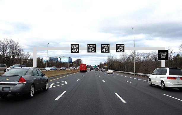 Figure 26. Photo. Second picture in the congestion ahead scenario (Washington-based sign). The figure shows a four-lane highway with active traffic management signs over each lane and a changeable message sign on the gantry to the right. The speed limit sign over the left lane is "SPEED LIMIT 60 MPH," and the other three lanes have a speed limit sign that shows "SPEED LIMIT 45 MPH." The CMS shows "REDUCED SPEED ZONE."