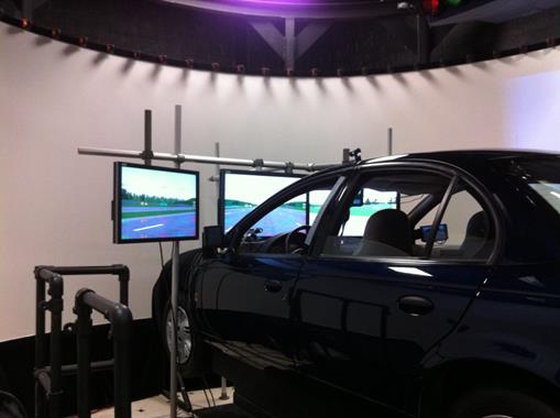 Figure 77. Photo. The FHWA Highway Driving Simulator with LCD monitors. This figure shows the Federal Highway Administration Highway Driving Simulator, which is a sedan with three liquid crystal display monitors arrayed in front of the windshield.
