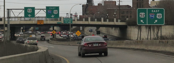 Ramp from I-35E southbound to I-94 and US 52, Saint Paul, MN. This photo shows an example of explicit, simplified signing, sometimes referred to as “positive guidance,” where multiple signs are provided, including a ground-mounted exit direction sign and overhead exit direction sign with angled down arrows.