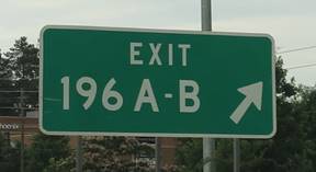 Figure 15-A. Photo. Exit gore sign with standard arrangement. This sign includes the directional arrow placed to the right of the exit number and letters.