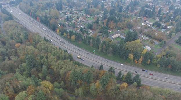 Photo. Example video still from an unmanned aerial vehicle at site 43-1. This aerial photo consists of four interstate lanes, with the rightmost lane being an exit-only lane. Three attributes are present: auxiliary lanes—attribute 4110; exit with downstream split—attribute 4222; and guide signs for option lanes—attribute 5130.