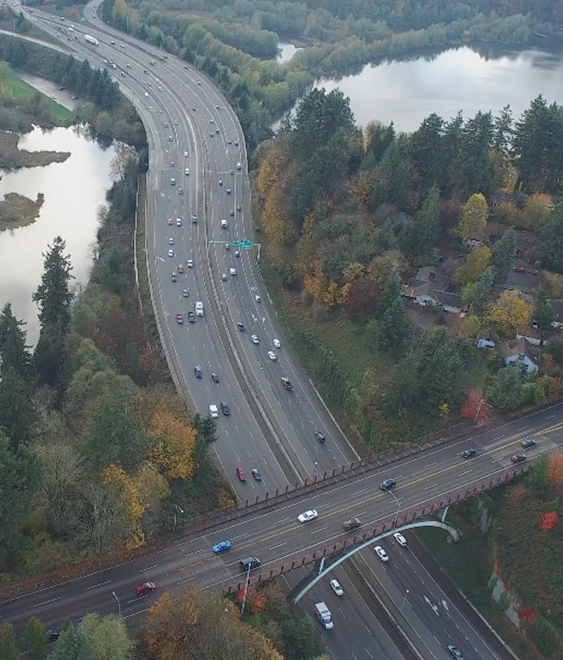 Photo. Example video still from an unmanned aerial vehicle at site 43-2. This aerial photo consists of four lanes, with the rightmost lane being an exit-only lane, and the adjacent lane being an option lane. Three attributes are present: auxiliary lanes—attribute 4110; exit with downstream split—attribute 4222; and guide signs for option lanes—attribute 5130.