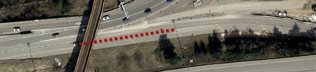 Photo. The use of a lane addition taper (marked with a broken red line) not delineated with dotted extension lines. This aerial photo pictures a lane addition taper not delineated with dotted extension lines. In figure 80, the taper is marked with a superimposed dotted red line.