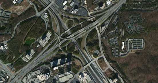 Photo. Aerial view of location 4. This aerial photo shows a modified cloverleaf interchange with direct-connection ramps for primary movements. The interchange features several braided connections to adjacent service interchanges, and access is provided to and from interchanges from all directions of all freeways.