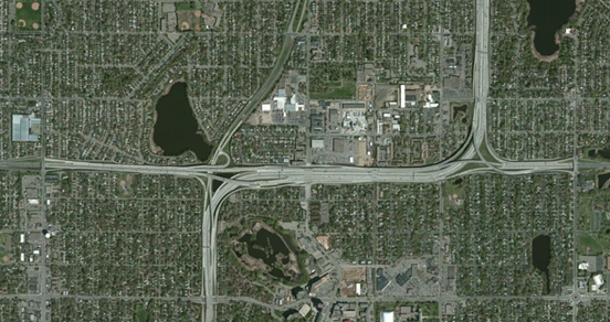 Photo. Aerial view of location 9. This aerial photo shows an interchange that fully separates through movements for both intersecting routes. Despite its extremely constrained size, the interchange sacrifices little in the way of readily discernible geometry.