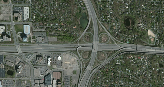 Photo. Aerial view of location 11. This aerial photo shows an interchange that serves interstate high-occupancy vehicle and tolling lanes barrier-separated section with ramps. The interchange features two direct-access ramps, serving both northbound and southbound directions of the highway and, in the westbound direction of the interstate, access to a local roadway.