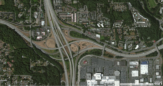 Photo. Aerial view of location 13. This aerial photo features a junction characterized by three distinct treatments of the upstream exit to a service interchange with downstream exit-only—including option lane—within the system interchange. A southbound left exit for a major movement is a compound exit, with a heavy-occupancy vehicle lane adjacent to the general-purpose exiting lane.
