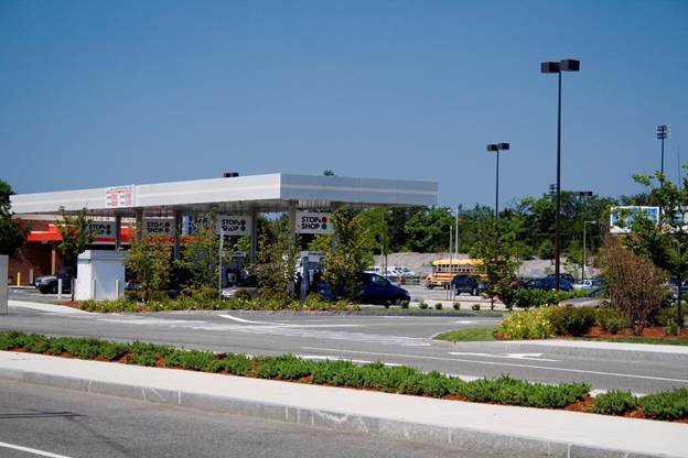 Photo. RIRO stop-controlled intersection. This photograph shows a street-level view of a section of multilane, median-divided urban road. The camera view is looking across the median to a commercial driveway on the other side of the road. The median, with curbs and plants, extends in front of the driveway, blocking left-turning drivers from entering the driveway and preventing exiting drivers from turning left.