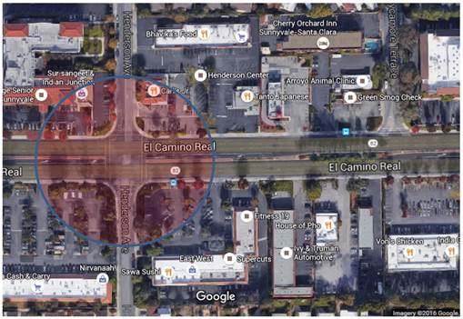 Aerial view of the street El Camino Real and its intersection with the smaller street, Henderson Avenue. There are numerous businesses with driveway entrances along El Camino Real near the intersection. The intersection is emphasized in the picture by a circle with shading inside.