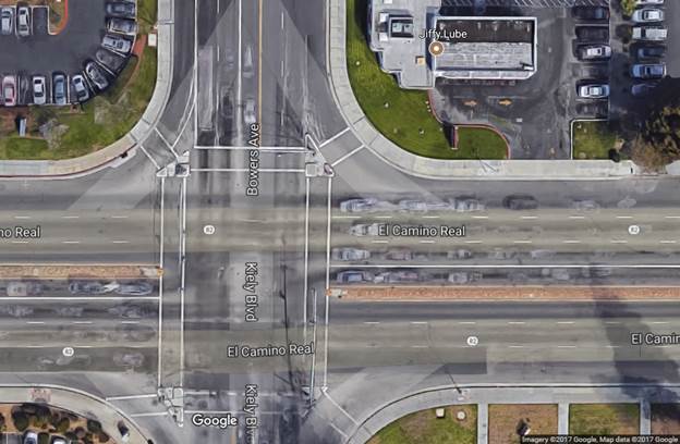 Aerial view of a four-leg urban intersection. The mainline, El Camino Real, is a six-lane median-divided roadway and the cross street, Kiely Boulevard/Bowers Avenue, is a four-lane roadway. Immediately before the intersection on the mainline approach corner, there is a driveway entrance on the right with limited corner clearance due to its proximity to the intersection.