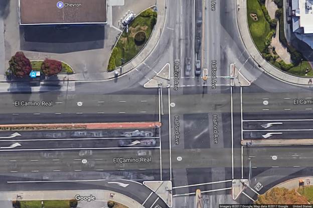 Aerial view of a four-leg urban intersection. The mainline, El Camino Real, is a six-lane median-divided roadway and the cross street, Halford Avenue, is a four-lane roadway. Immediately after the intersection on the mainline receiving corner, there is a driveway entrance on the right with limited corner clearance due to its proximity to the intersection.