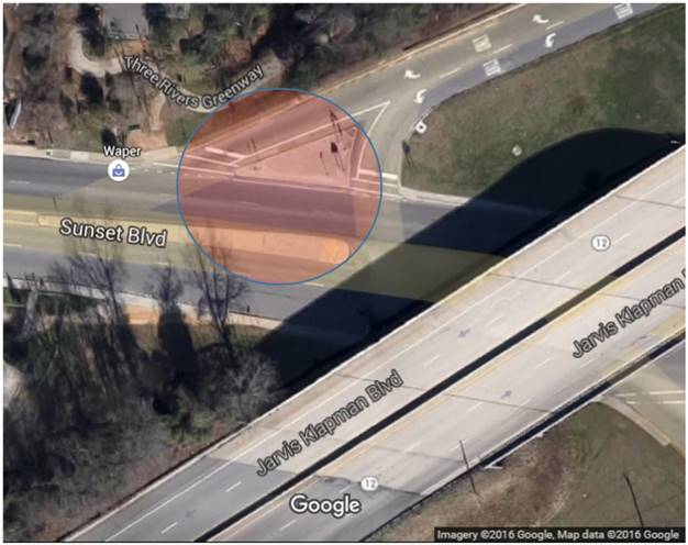 Bird’s-eye view of an intersection with an abnormal configuration. There is a major roadway with an east and west directional path. A limited-access highway passes over the major roadway in a northeast and southwest direction in the lower right corner of the screenshot. In the top portion of the screen shot an exit ramp comes from the north and intersects with the major roadway. The ramp splits into two separate lanes for exclusive right and left turning motions. A red translucent circle highlights the ramps’ intersection with the major roadway showing it is the intersection being verified.