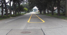 This photo shows an image of a road with edge line pavement markings. The center median is painted to reduce lane widths.