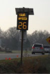 This is a photo of a dynamic sign that digitally displays the speed of the passing operating vehicle. The sign has a black background and the display text appears in yellow and it reads as follows: 'YOUR SPEED 26.'