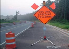 This is a photo of a speed-activated warning sign. When the speed limit is exceeded, the flashing lights on the sign are activated. The sign is an orange diamond that reads as follows: 'YOU ARE SPEEDING IF FLASHING.'