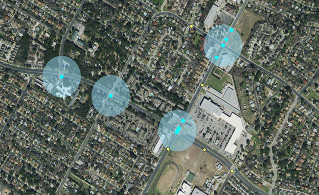 This figure is an aerial map of the Austin, TX, area with four transparent circles at four different intersections to demonstrate the inclusion of crashes occurring near an intersection that would be considered an intersection-related crash. Crashes are shown as blue dots when within the transparent circle and yellow dots when outside of the transparent circle.
