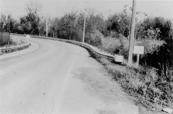 Figure 11. Typical Roadway with Roadside Hazard Rating Equal to 4. This picture depicts a two-lane road with a horizontal curve bordered by a guardrail fairly close to the edge of pavement. 
