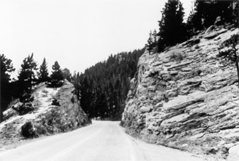 Figure 14. Typical Roadway with Roadside Hazard Rating Equal to 7. This picture depicts a two-lane road that has been cut through the side of a mountain - boulders directly abut the road on both sides. 
