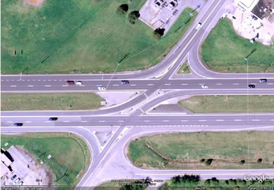 Figure 2. Photo. Channelization for left turns from the highway and right turns from the minor road. This photo shows a satellite view of a main intersection. Channelization is shown, which prevents direct left-turn and through movements from the minor road but allows left-turn movements from the highway onto the minor road. Other features are deceleration lanes for left and right turns from the highway and acceleration lanes for right turns from the minor road.