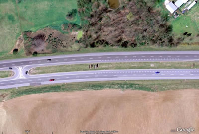 Figure 3. Photo. Directional U-turn channelization at the RCUT observed in this study. This photo shows a satellite view of one of the U-turn channels of the restricted crossing U-turn (RCUT) intersection observed in this study. Channelization is shown, which prevents conflicts between vehicles making U-turns from the northbound direction to the southbound direction and vehicles turning from the southbound direction to the northbound direction. Wide deceleration and acceleration lanes for U-turning vehicles are also present.