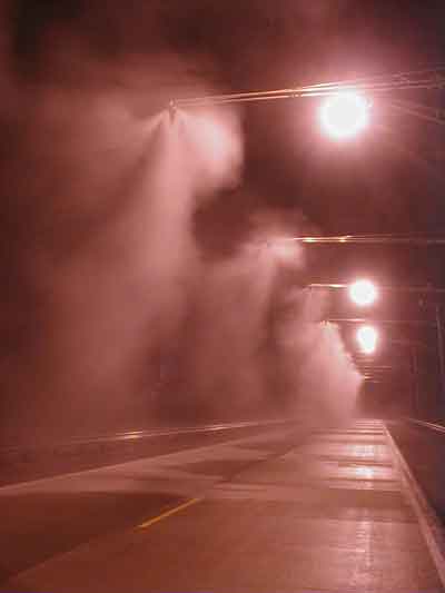 Photo. Smart Road overhead lighting system and fog towers starting to make fog. Click here for more detail.