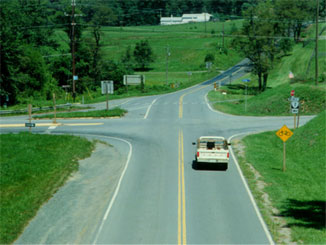 This picture shows a vehicle approaching a four-way intersection. There does not appear to be any traffic signals or stop signs controlling the vehicle's travel through the intersection.