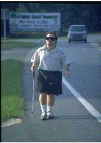 Figure 36. Without adequate facilities, vision-impaired pedestrians, such as the blind man walking in the shoulder of this two-lane highway with traffic approaching from behind him, are at increased risk 