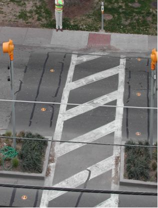 Second photo shows a view from the sky of a zebra crossing (two parallel lines running perpendicular to the roadway with diagonal lines inside the outer two) with in-roadway warning lights located on the outside of the crosswalk.