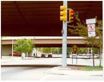 Pedestrians are restricted from continuing straight and are encouraged to cross left to avoid a traffic merge lane.