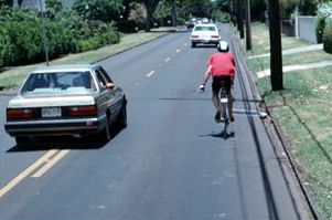 1) This photograph shows a bicyclist riding in the right third of a vehicle lane, and a vehicle has crossed the roadway centerline in order to pass the bicyclist.