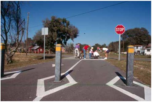 Signs, bollards, and trail and crosswalk markings alert both motorists and bicyclists to this midblock trail crossing.