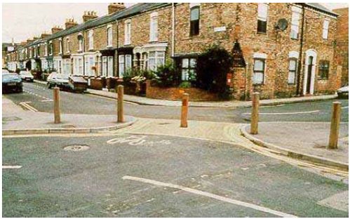 Diagonal road closures/diverters limit vehicular access but allow emergency vehicles to enter through removable bollards.