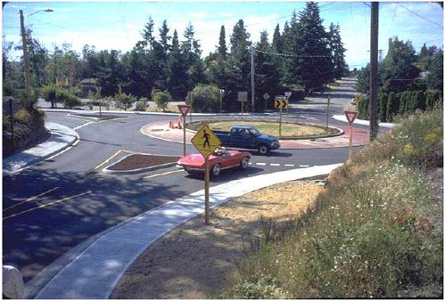 The splitter islands should be raised and landscaped to prevent left-turning vehicles from taking a shortcut across the island.