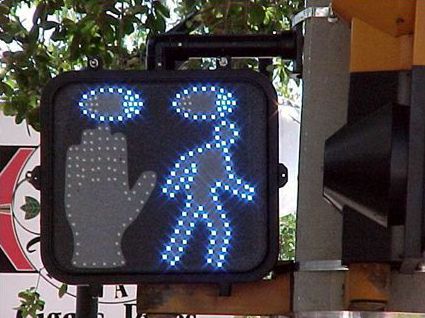 The animated eyes display has two lighted blue eyes at the top of the box, a hand (not yet flashing) on the left side, and LED lights outlining a pedestrian on the right.