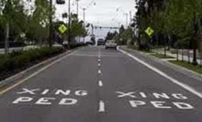 The picture shows the following text painted on the pavement: "PED XING".