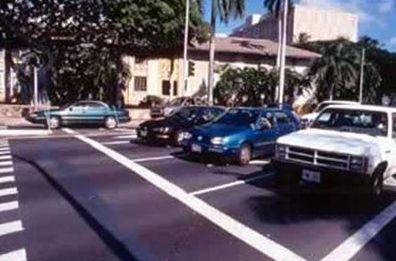 The picture shows a STOP bar painted at a intersection, with several vehicles stopped behind the white painted lines.