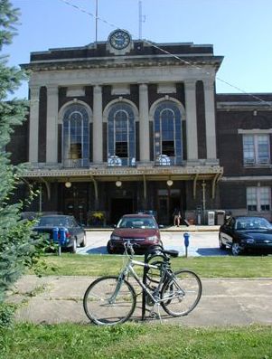 Picture shows a bike rack with bikes parked outside a historic train depot.